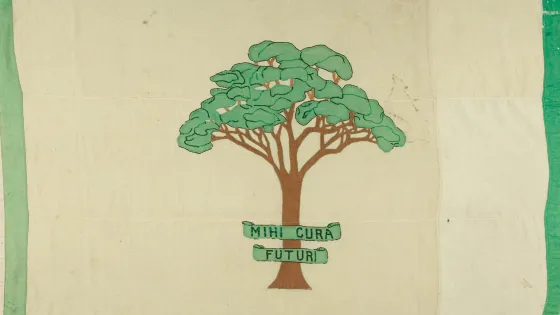 A fabric banner featuring a stylized green tree on a cream background with a banner around the trunk reading "MIHI CURA FUTURI."
