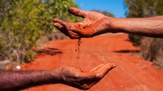 Photo: Adobe Stock A hand pours red earth onto another hand