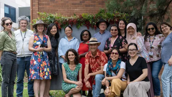 A group of academics, students and staff gather for a photo.