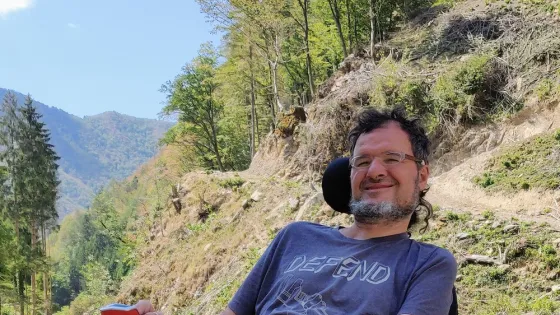 Dabiz sits in a wheelchair in front of a river