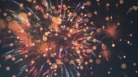 Colorful fireworks bursting in a night sky with visible light trails and bokeh effects.