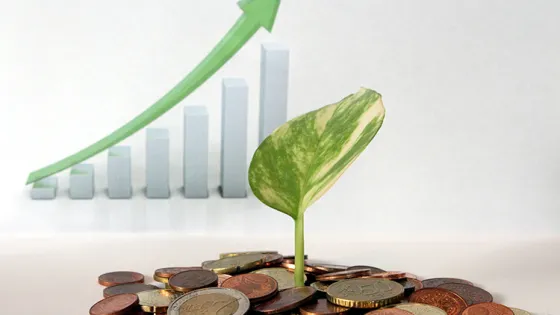A plant growing out of a pile of coins with a backdrop of a rising bar graph and upward arrow, symbolizing economic growth or investment success.