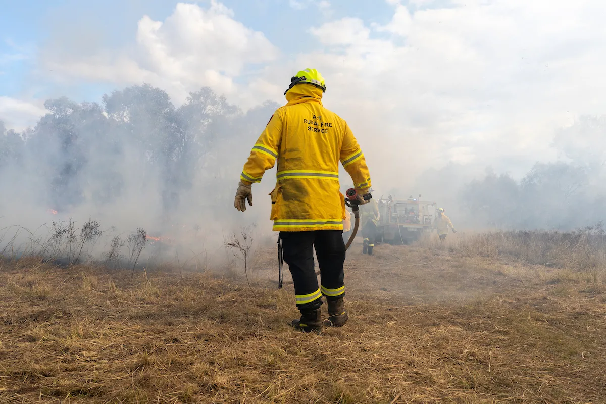 Firefighter in a dry field among smoke
