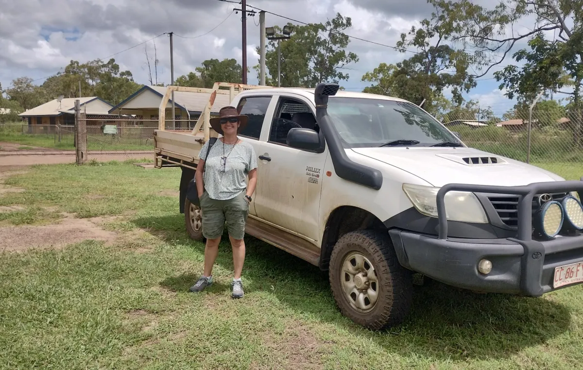 A woman in a hat standing next to a ute