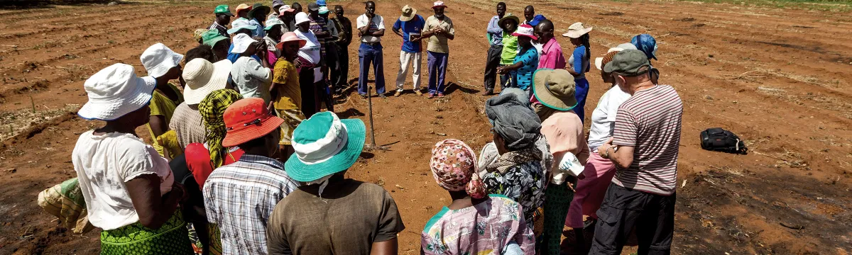 People gather in a circle on a dusty field.
