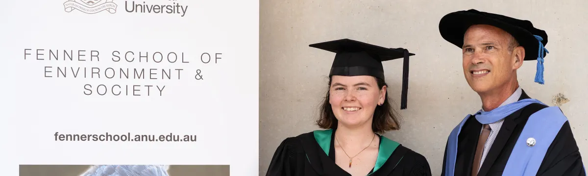 A student poses for a photo in her graduation attire with her supervisor.