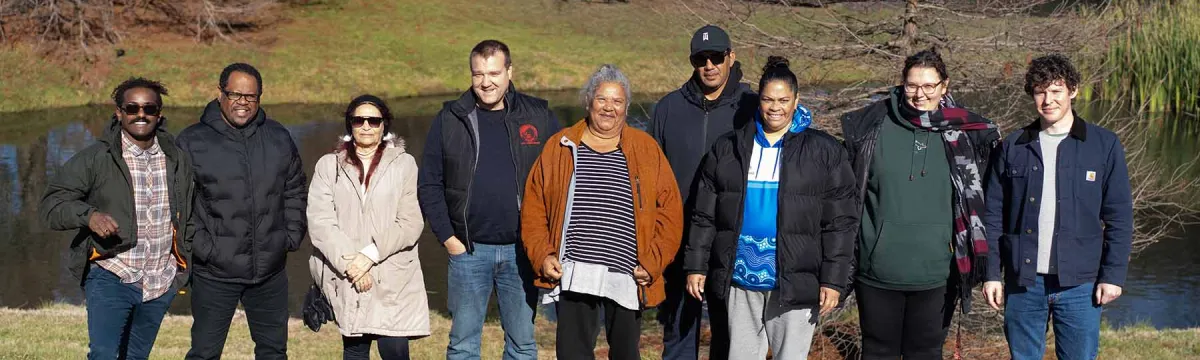 Researchers and collaborators stand in front of a pond at the ANU Campus.