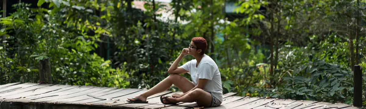 A student sits on a bridge in a tropical forest in Vietnam.