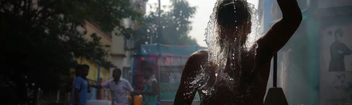 A man splashes water over himself in a street.