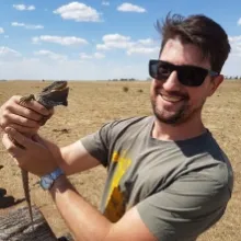 Geoff Heard smiles and holds a lizard