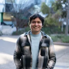 Wil Laura stands in a plaid shirt and smiles at the camera.