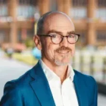 Tim Baynes looks at camera and wears a blue suit