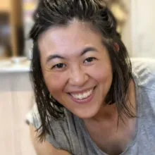 Eri smiles at the camera. She is wearing a grey t-shirt.