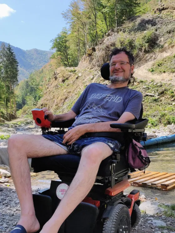 Dabiz sits in a wheelchair in front of a river