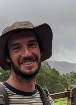 Nick Wilson with a brown hat on and forest in the background.