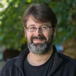 Jonathan smiles at the camera. He has a beard and wears glasses.