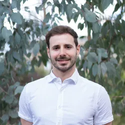 Eric stands in front of eucalyptus leaves on campus.