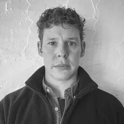 Portrait of PhD researcher, Sam Provost, facing the camera. Photo is in black and white.