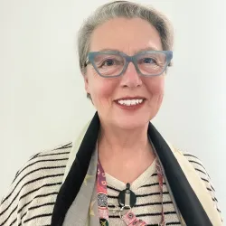 Portrait of Ruth Beach, she is wearing a striped shirt and glasses