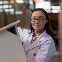 Kara with a nest box, wearing a white lab coat.