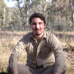 Tim sits in a grassy woodland.