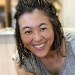 Eri smiles at the camera. She is wearing a grey t-shirt.