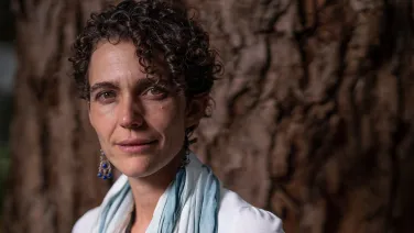 Researcher, Marta Yebra, stands in front of a tree.