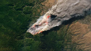 A satellite image of a fire sweeping across a forested landscape.
