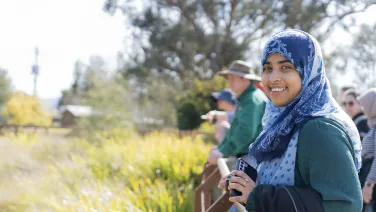 A student stands in front of a reedy pond smiling at the camera.