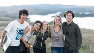 A group of students stand in front of a lake.