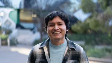 A student smiles for the camera on campus at ANU.