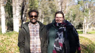 Two researchers pose for a photo outside.