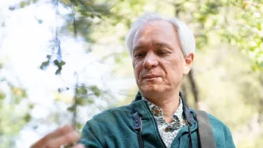 Professor Luis Miguel Renjifo inspects the leaves and fruit of a tree at the Botanic Gardens