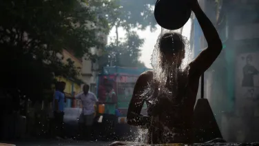 A man splashes water over himself in a street.